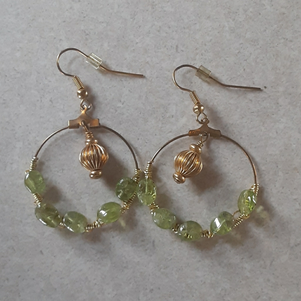 Gold color earrings that have light green rocks